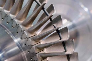 Close-up of a machined aerospace turbine rotor showing aerofoil blades and fir-tree root slots