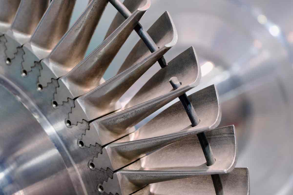 Close-up of a machined aerospace turbine rotor showing aerofoil blades and fir-tree root slots