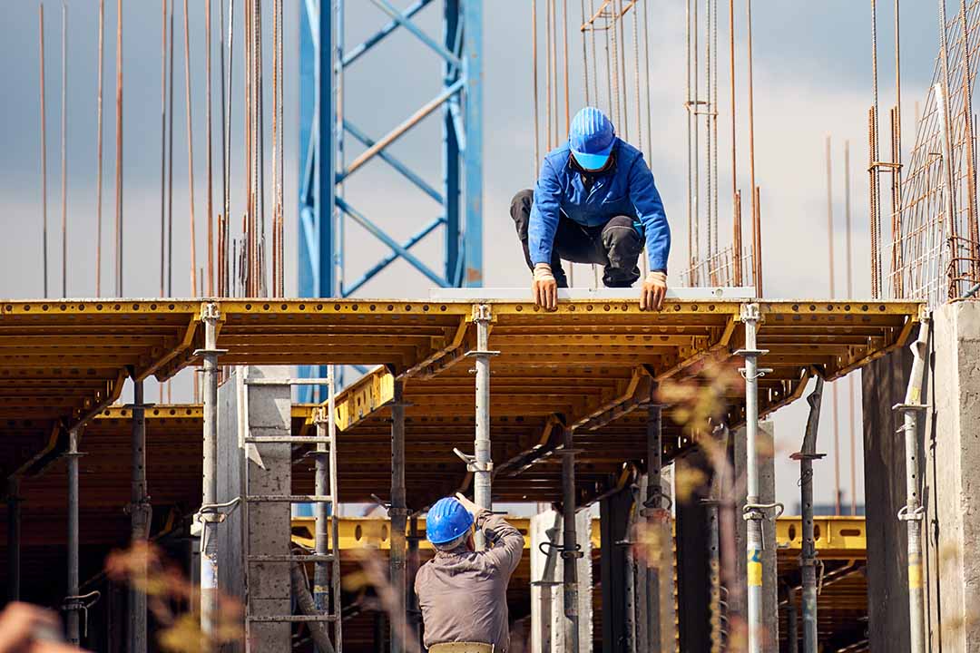 Construction Precision Machining Services - construction worker working on a high building