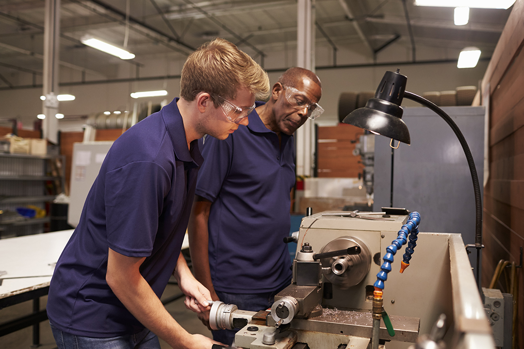engineer training male apprentice on milling machine