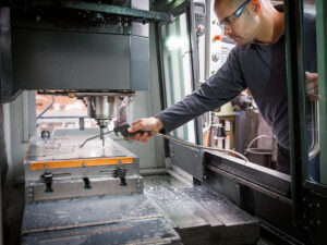 knife factory worker spraying liquid onto machiner