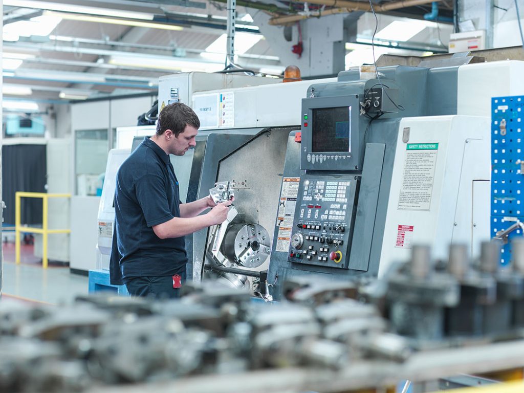 Industries Served - male worker inspecting parts on cnc lathe machine