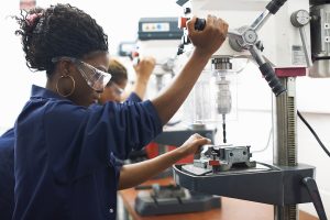 students using drilling machines in college workshop